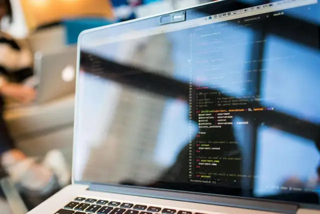 Programista kod zawodu, pisze kod na laptopie. Widać fragment ekranu z kodem w języku Ruby.