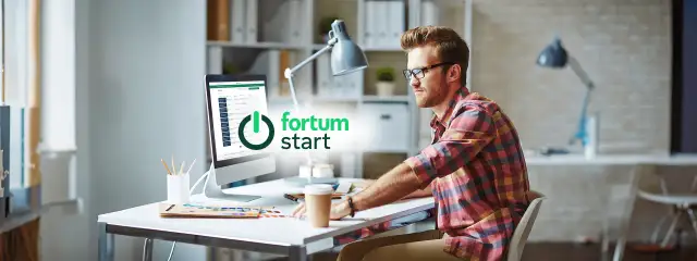 Mężczyzna przy biurku pracuje na komputerze z logo Fortum.