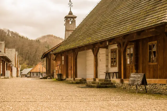 Drewniana zabudowa skansenu, wieża z wiatrowskazem i tablica "Pamiątki Regionalne" - tak z czego słynie Sanok.