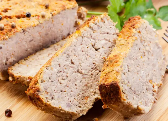 Domowy pasztet według starego przepisu, pokrojony w plastry, z przyprawami i natką pietruszki.