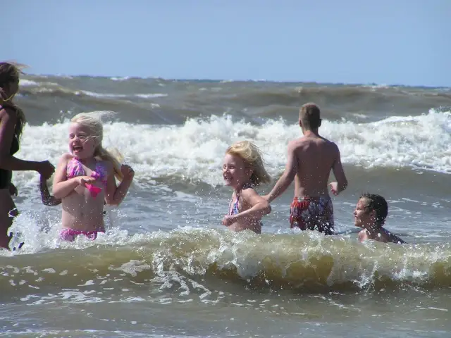 Dzieci bawią się w falach Bałtyku w słoneczny dzień.