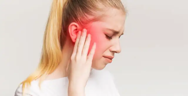 Kobieta z opuchlizną i zaczerwienieniem w okolicy ucha, wskazującym na zapalenie nerwu trójdzielnego.