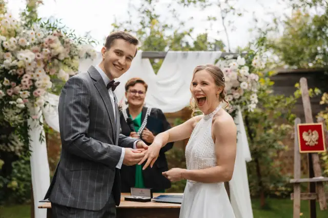 Para młoda wymienia obrączki podczas ceremonii ślubnej na zewnątrz.