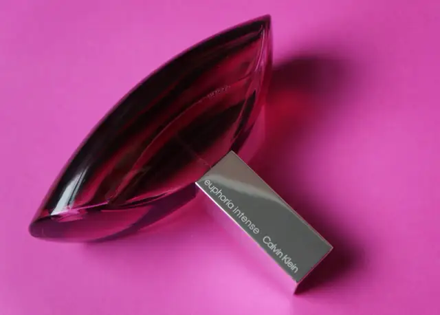 Różowa butelka Euphoria Intense Calvin Klein, woda perfumowana, lśni na tle intensywnego różu.