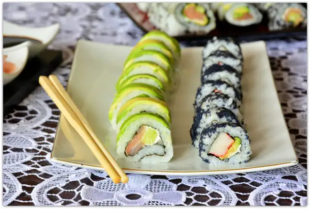 Jak pokroić awokado do sushi? Na talerzu sushi z awokado i czarnym kawiorem, obok pałeczki.
