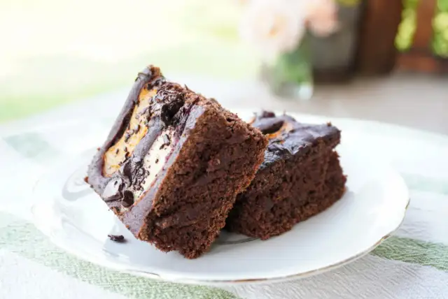 Dwa kawałki czekoladowego ciasta z kremowym nadzieniem, idealne na przepis na ciasto bezglutenowe.