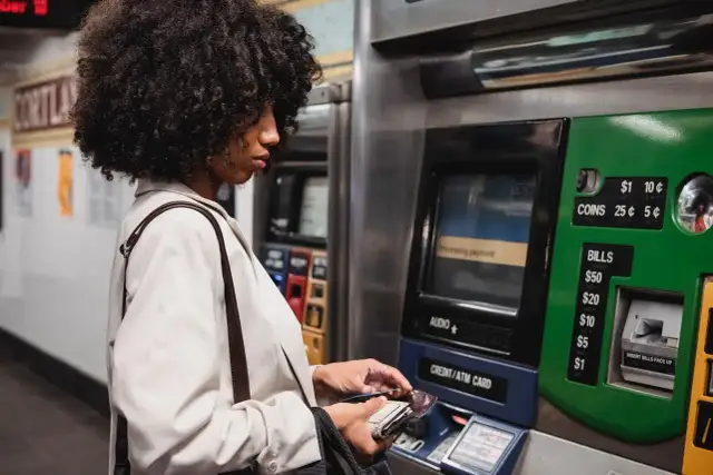 Kobieta z burzą włosów dokonuje płatności na stacji metra, korzystając z bankomatu. To jej millenium wypłata z innego bankomatu, bo ten jest bliżej.