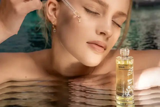 Kobieta z pipetką aplikuje serum na twarz, obok buteleczka serum Senelle.
