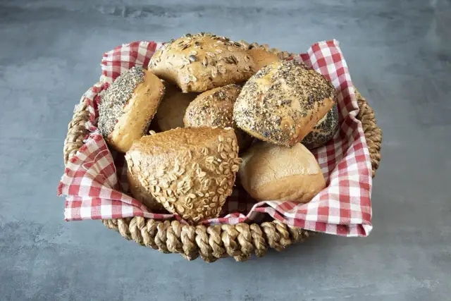 Kosz pełen bułek z ziarnami i płatkami owsianymi. Czy bułki są zdrowe? Te wyglądają apetycznie i bogato w składniki odżywcze.