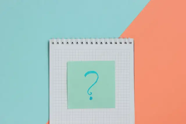 Notatnik z pytajnikiem na zielonej karteczce. Tak jak wyglądają badania do szkoły średniej – pełne pytań i niepewności.