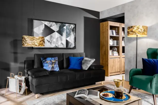 Nowoczesny salon w stylu holenderskim: czarna sofa, złote lampy, drewniana biblioteczka i zielony fotel.