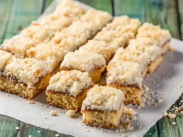 Szybkie ciasto na niedzielę do kawy, pokrojone w kostkę, z kruszonką i dżemem. Idealne na leniwe popołudnie.