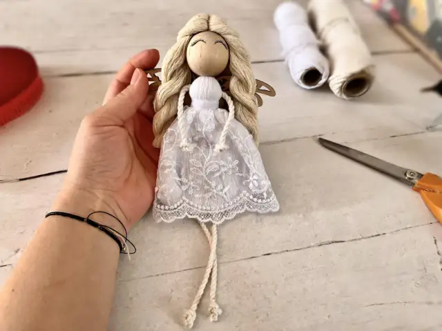 Ręcznie robiony, prosty anioł z makramy, z koronkową sukienką i drewnianą głową, gotowy do zawieszenia.