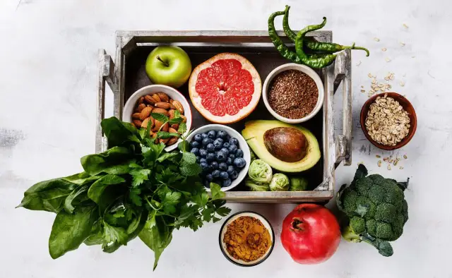 Zielone jabłko, borówki, awokado – jakie owoce można jeść na noc? W drewnianej skrzynce znajdziesz też migdały, grejpfruta i szpinak.