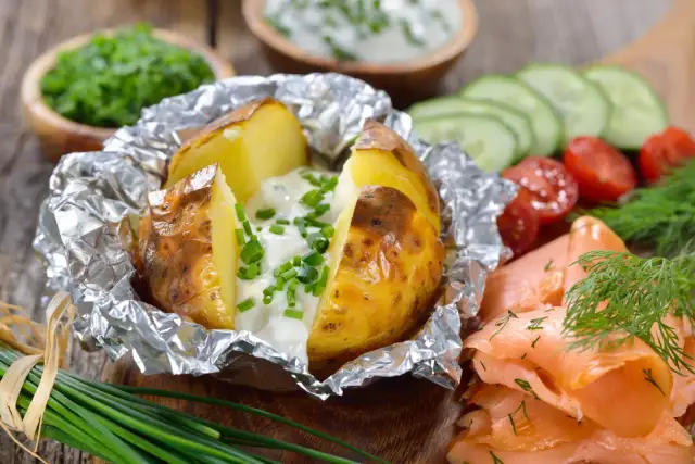 Pyszności na grilla: pieczony ziemniak z sosem, wędzony łosoś, pomidorki i ogórek. Idealne danie na letnie wieczory.