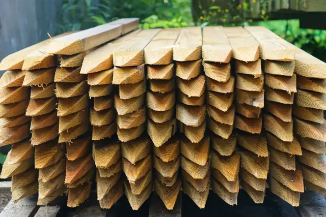 Stos drewnianych zaostrzonych palików geodezyjnych.