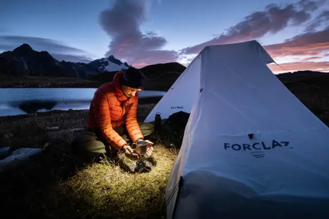 Wieczorne gotowanie przy namiocie, jezioro i góry w tle. Wady spania w namiocie to zimno i brak wygód, ale widok jest tego wart.