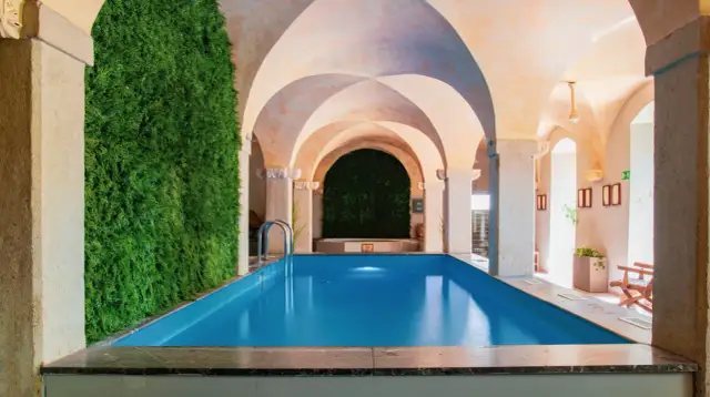 Relaks w hotelu spa na Dolnym Śląsku. Wnętrze z basenem, zieloną ścianą i łukowym sufitem.