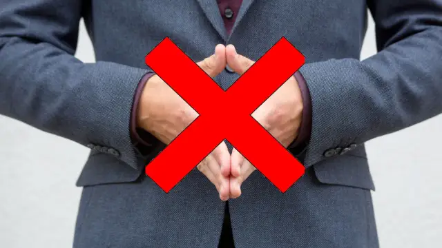 Postać w sztuce, mężczyzna w garniturze, z dłońmi złożonymi na piersi, na które nałożono duży czerwony znak "X".