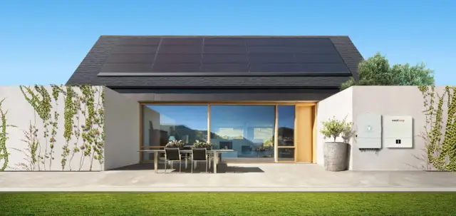 Nowoczesny dom z panelami słonecznymi na dachu i dwoma falownikami. Instalacja OZE zapewnia czystą energię.