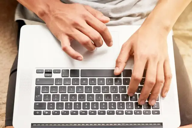 Dłonie na klawiaturze laptopa HP. Dowiedz się, jak odblokować klawiaturę w laptopie HP, gdy przestanie odpowiadać.