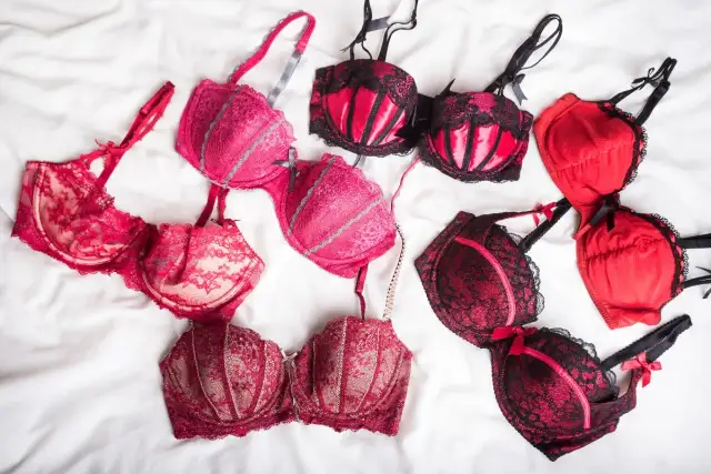 Kolekcja czerwonych i różowych biustonoszy, w tym seksowny biustonosz zbierający z koronką i satynowymi wstawkami.