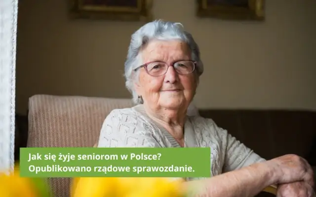 Uśmiechnięta starsza kobieta w okularach siedzi w fotelu.