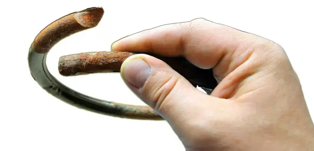 Dłoń trzyma zardzewiały fragment sprężyny, symbolizujący potrzebę wymiany sprężyn przód.