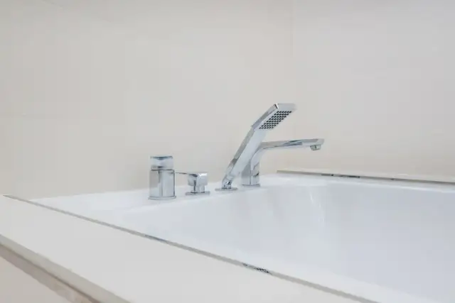 Elegancka bateria wannowa jednootworowa z chromowanymi elementami i słuchawką prysznicową, idealna do nowoczesnej łazienki.