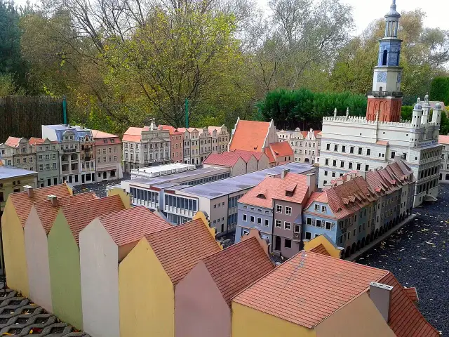 Miniaturowa zabudowa miejska z wieżą zegarową i kolorowymi domkami w skansenie.