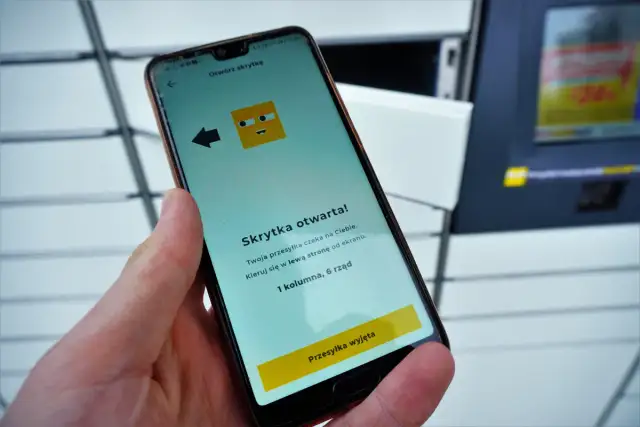 Dłoń trzyma smartfon z aplikacją InPost informującą o otwartej skrytce.