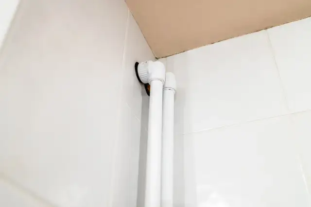 Białe osłonki na rury co, zamontowane przy białych kafelkach, tworzą estetyczne wykończenie instalacji.