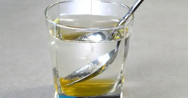 Szklanka wody z miodem i łyżeczką, naturalny sposób na to, jak poprawić trawienie.