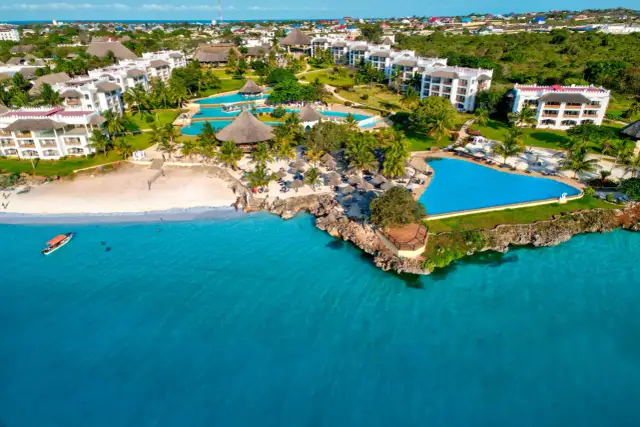 Widok z samolotu na tropikalny kurort na Zanzibarze z białymi budynkami, basenami i plażą nad turkusowym oceanem.