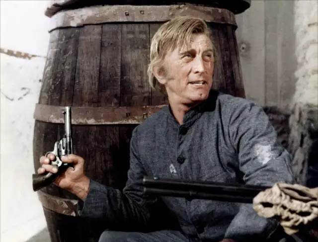 Kirk Douglas w westernowym filmie, z rewolwerem w dłoni, gotów do akcji.