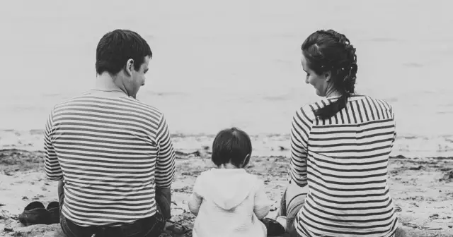 Rodzina siedzi na plaży, patrząc na wodę. Czy dusza wie co dzieje się w rodzinie, gdy wspólnie spędzają czas?