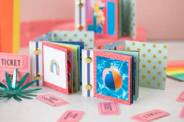 Kolorowe mini albumy na zdjęcia z tęczą i piłką plażową, otoczone biletami.