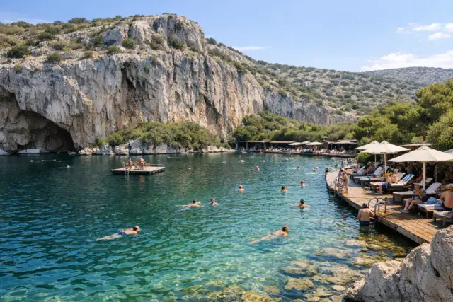Ludzie kąpią się i relaksują nad krystalicznie czystym jeziorem Vouliagmeni, otoczonym skalistymi zboczami i zielenią.