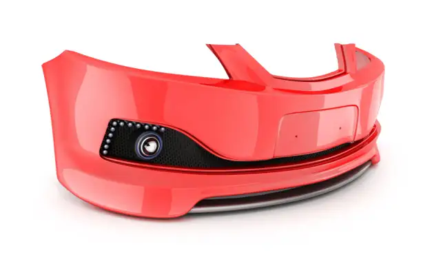 Czerwony zderzak samochodowy z czarną siatką i okrągłym elementem.