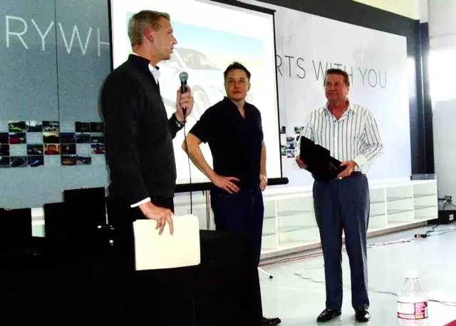 Elon Musk, jeden z tych, kto stworzył Teslę, stoi obok dwóch mężczyzn podczas prezentacji.