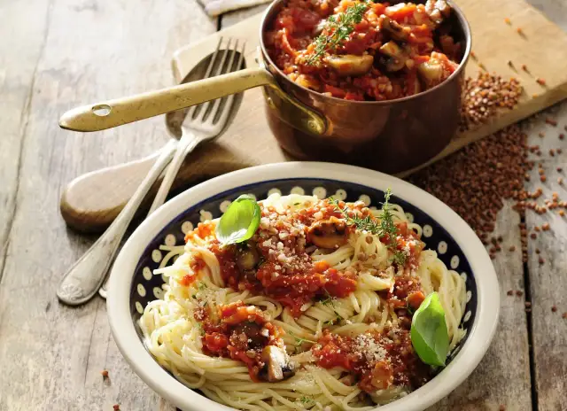 Wegańskie spaghetti bolognese z pieczarkami i ziołami, podane w misce z ozdobnym wzorem.