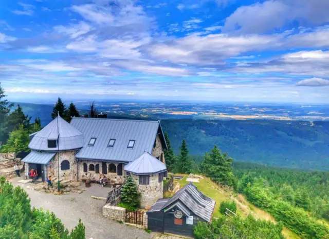 Kamienny schronisko na szczycie góry, z którego roztacza się piękny widok. Idealne miejsce na odpoczynek po wędrówce, zastanawiając się, jakie szlaki w Szklarskiej Porębie wybrać.