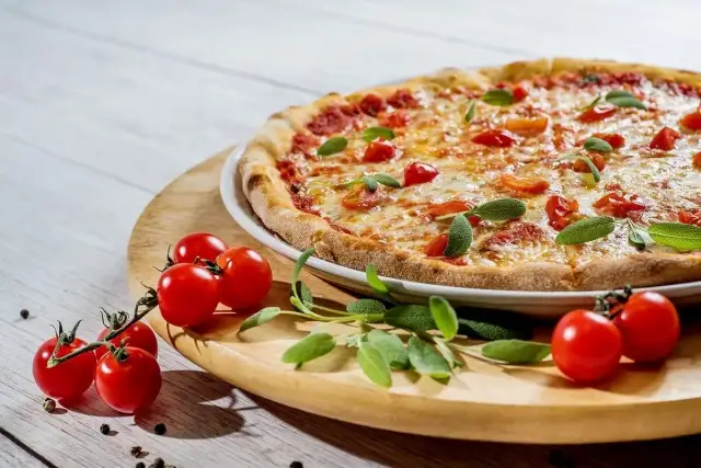 Pyszna pizza 32 cm z pomidorkami i bazylią. Ile kawałków ma pizza 32 cm? Zazwyczaj 8, idealna na spotkanie.
