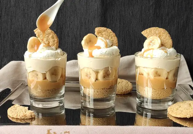Pyszny deser bananowy przepis w szklaneczkach: warstwy ciastek, karmelu, bananów i bitej śmietany. Idealny na deser!