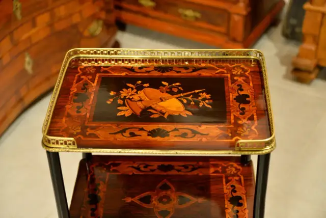 Stolik z bogatym zdobieniem drewna drewnem, przedstawiającym bukiet kwiatów i instrument muzyczny.