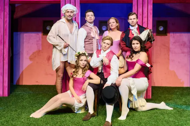 Aktorzy w strojach teatralnych, którzy pracują w teatrze, pozują na scenie.