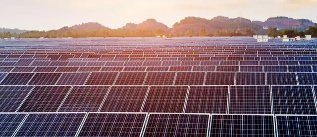 Ogromne pole paneli fotowoltaicznych do 150 kW bez pozwolenia na budowę, lśniące w słońcu na tle gór.