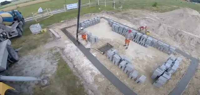 Budowa fundamentów: betonowanie i układanie bloczków przez robotników.