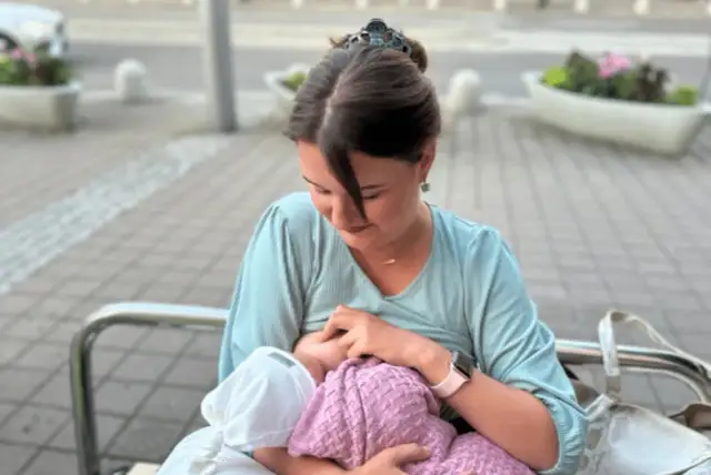 Mama karmi piersią dziecko na ławce w parku. Naturalne karmienie piersią w miejscu publicznym to piękny widok.