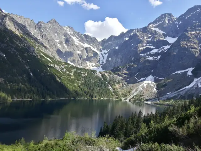 Majestatyczne góry otaczają spokojne Morskie Oko, odbijając w swojej tafli skaliste szczyty i zielone lasy.